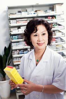 Close-up of a female pharmacist holding medicine in a store room