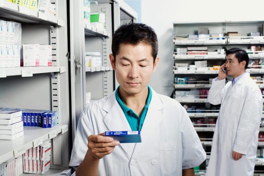 Male pharmacist holding medicine in a store room