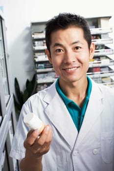 Portrait of a male pharmacist holding a bottle in a store room