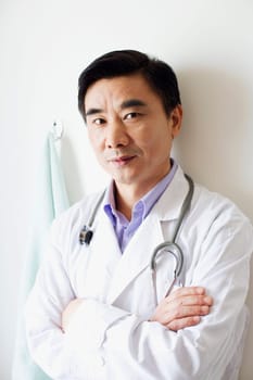 Portrait of a male doctor leaning against a wall