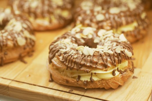 Cream-filled pastries topped with chocolate and nuts on display.