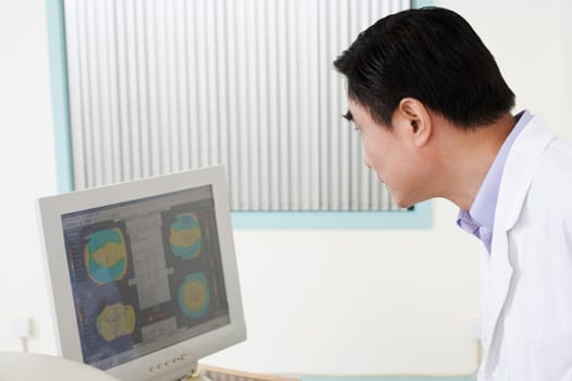 Side profile of a male doctor looking at a computer monitor