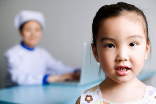 Portrait of a girl and a nurse working on a laptop in the background