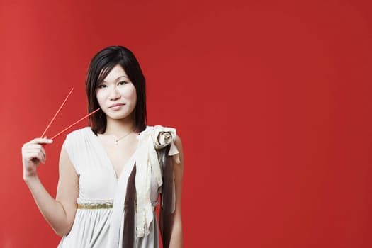 Portrait of a young woman holding chopsticks