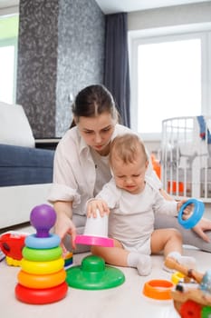 Young mother and cute baby playing on floor at home