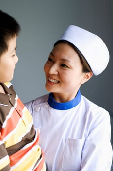 Close-up of a female nurse and a boy smiling and looking at each other
