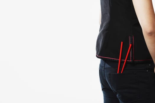 Mid section view of a young woman with chopsticks in her pockets