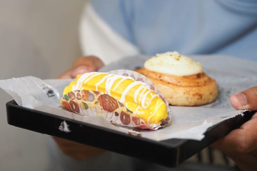 Someone holds a tray with two sweet treats ready to enjoy