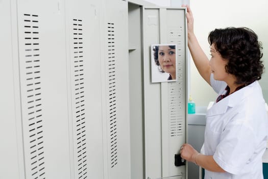 Side profile of a female looking at a mirror on the door of a locker