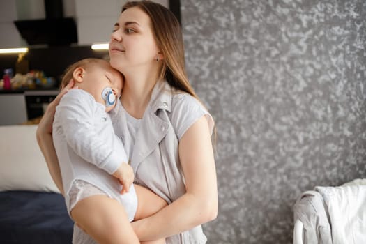 Infant baby falled asleep in mother arms. Home photo. Lifestyle portrait.