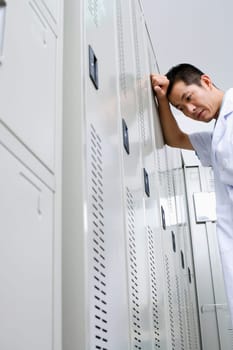Low angle view of a doctor leaning against a locker