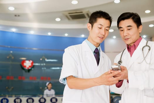 Close-up of two male doctors looking at a personal data assistant