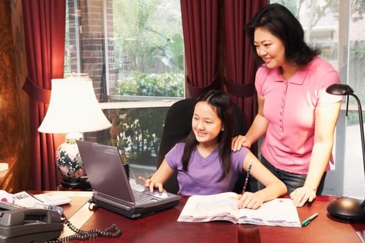 High angle view of a girl and her mother in front of a laptop
