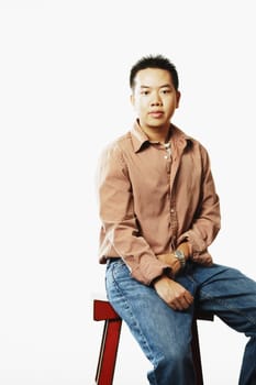 Portrait of a young man sitting on a stool