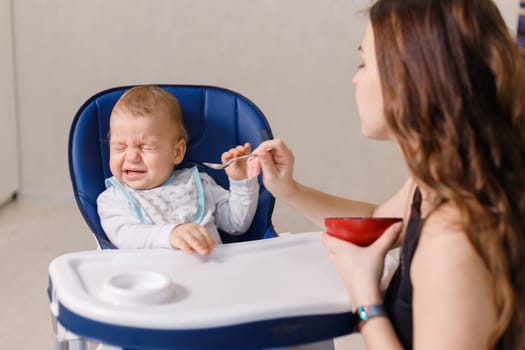 Naughty caucasian infant kid is fussy and refuses to eat.