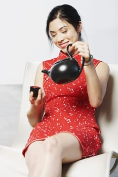 Close-up of a young woman holding a tea cup and a tea kettle