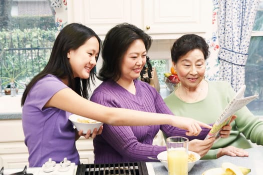 Close-up of a mother with her daughter and a senior woman reading a newspaper