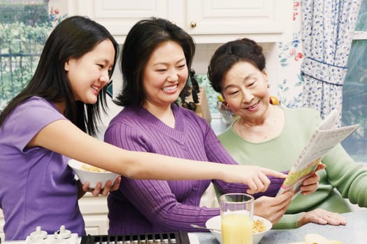 Close-up of a mother with her daughter and a senior woman reading a newspaper