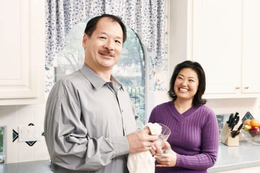 Portrait of a senior man cleaning a glass with a mature woman standing behind her