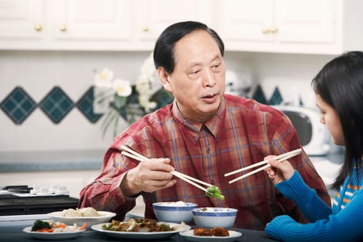 Grandfather and his granddaughter sitting at a table