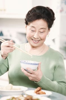 Close-up of a senior woman holding chopsticks and a bowl