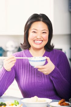 Portrait of a mature woman holding a bowl with a pair of chopsticks
