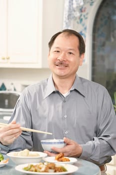 Portrait of a senior man holding a bowl with a pair of chopsticks