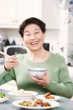 Portrait of a senior woman holding a pair of chopsticks and a bowl