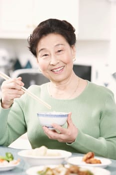 Portrait of a senior woman holding a pair of chopsticks and a bowl
