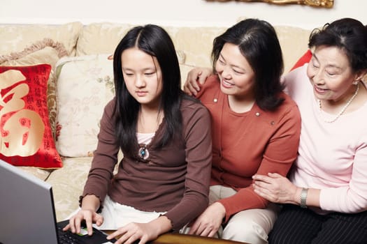 Close-up of a daughter using a laptop with her mother and her grandmother sitting beside her