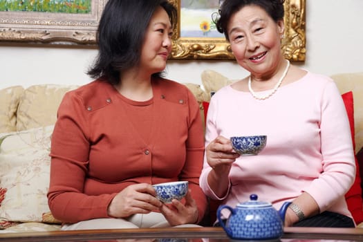 Close-up of a mother and her daughter holding tea cups