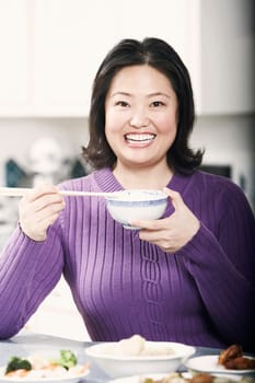 Portrait of a mature woman holding a bowl with a pair of chopsticks