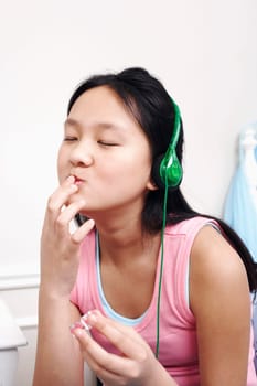 Close-up of a girl applying lipstick and listening to music