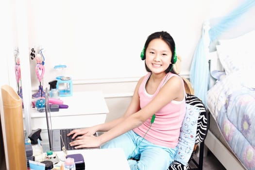 Portrait of a girl using a laptop and listening to music