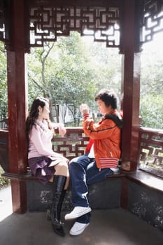 Side profile of a teenage boy taking a photograph of a young woman with a video camera