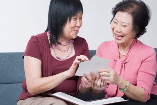 Close-up of a mature woman and a senior woman looking at photographs and smiling