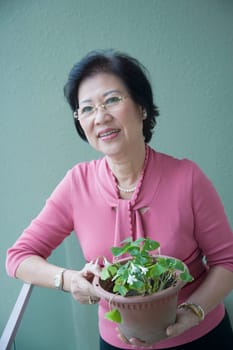 Senior woman holding a potted plant and smiling