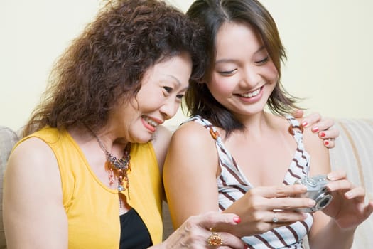 Close-up of a senior woman and her granddaughter looking photographs in a digital camera