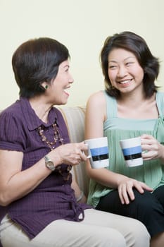 Senior woman and her granddaughter holding cups and smiling