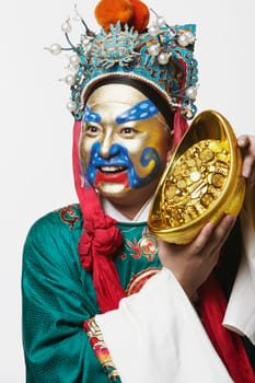 Close-up of a male Chinese opera performer holding a bowl full of gold coins