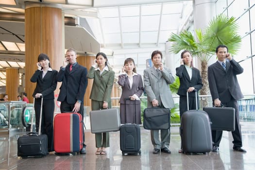 Business executives talking on mobile phones at an airport lounge