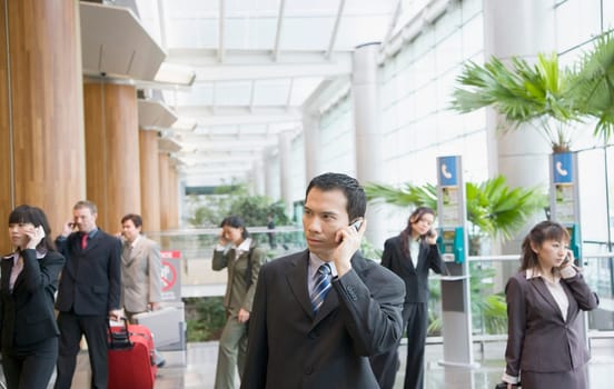 Business executives talking on mobile phones and leaving an airport lounge