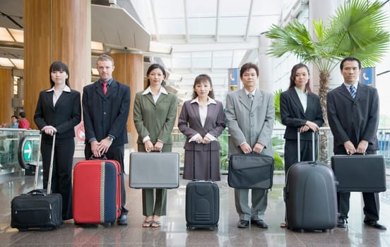 Business executives standing at an airport lounge with their luggage