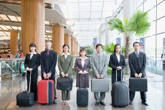 Business executives standing at an airport lounge with their luggage