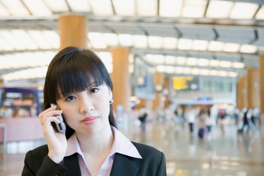 Portrait of a businesswoman talking on a mobile phone at an airport lounge