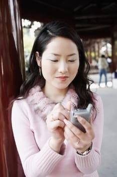 Close-up of a young woman operating a mobile phone with a digitized pen smiling