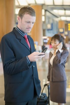 Side profile of a businessman using a mobile phone at an airport lounge