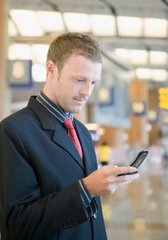 Side profile of a businessman using a mobile phone at an airport lounge