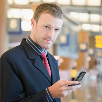 Portrait of a businessman using a mobile phone at an airport lounge