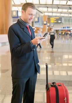 Side profile of a businessman using a mobile phone at an airport lounge